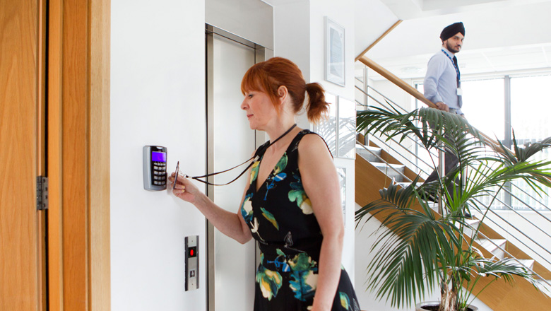 A woman entering a room using an access control card and keypad