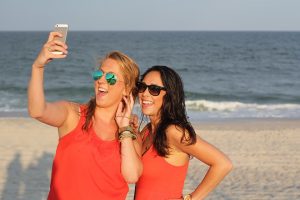 2 girls taking a picture of themselves on the beach.