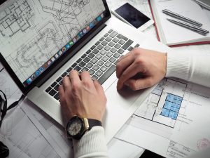 A man working on a home blueprint on a laptop.