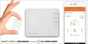 An Alarm.com temperature sensor and thermostat, with the Alarm.com app open on a smartphone.