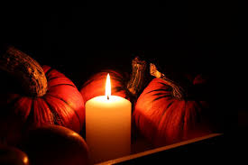 A candle burning between pumpkins