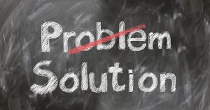 A chalkboard sign with the word "Problem" crossed out and replaced by the word "Solution"