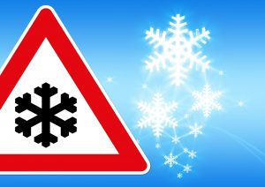 A traffic sign with a snowflake on it, with snow falling in the background